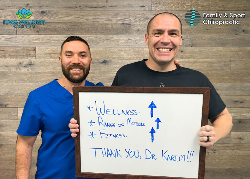 Provider and patient standing next to each other smiling. The patient holds a signs that states how his wellness, range of motion, and fitness have all improved thanks to the help and guidance from Dr. Karim and the regenerative powers of ozone blood therapy near Cedar Rapids.