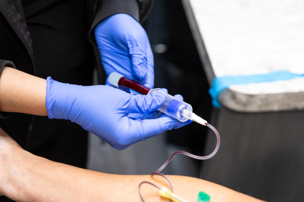Medical provider wearing gloves draws blood from a patient's arm to spin and centrifuge and use it for PRP + Ozone Therapy near Cedar Rapids to help with anti-aging benefits and provide relief from allergies
