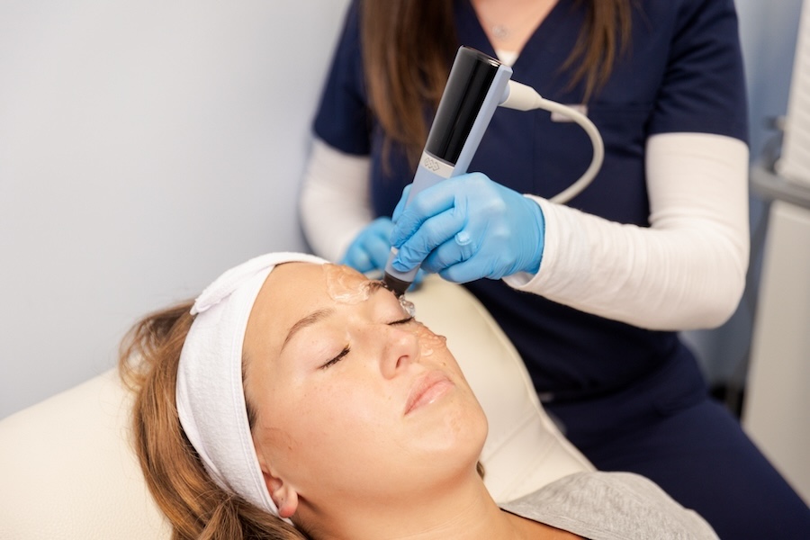 Medical provider with blue gloves applies exion on to patient's face for facial rejuvenation near Iowa City