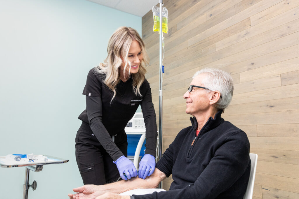 Blonde nurse wearing purple gloves places IV in patients arm for ozone therapy near Cedar Rapids so he can find relief from fatigue, viruses, immune dysfunction, and joint pain