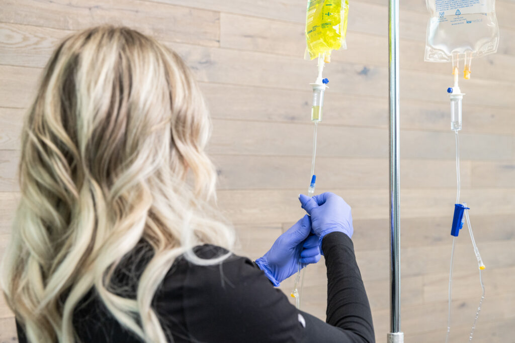 Provider attaches tube to the infusion bag for IV therapy near Iowa City in the office of a wellnesss center.