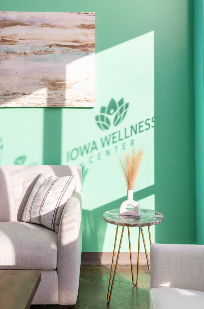 Room painted green with white couch and the shadow of the Iowa Wellness Center sign is in view as patients wait for a consultation for skin tightening in North Liberty