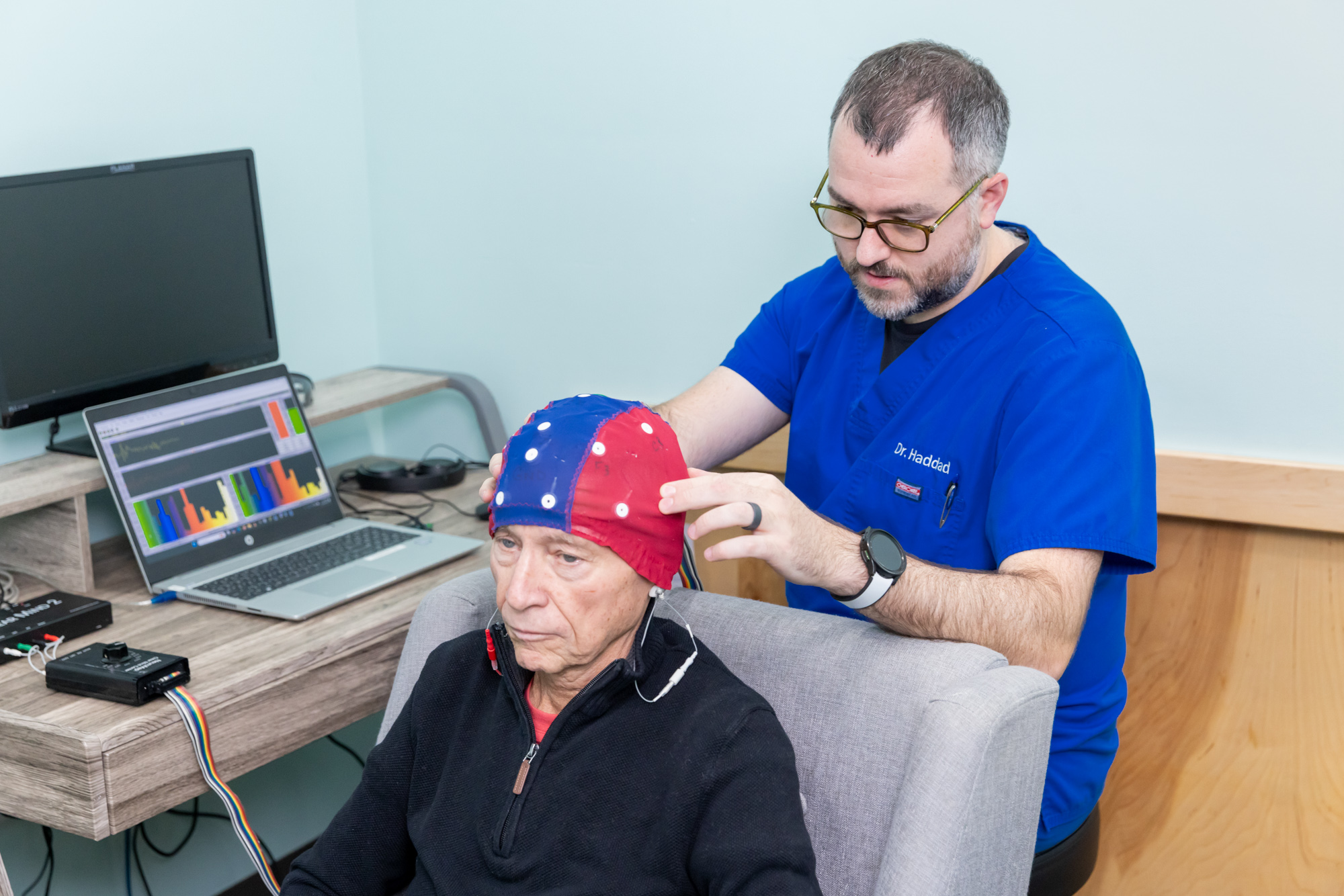 Provider places cap on patient's head as part of an appointment for neuromapping in North Liberty. This service measures brain wave activity to pinpoint where pain activity is present in patients struggling with neuropathy, and create a personalized treatment plan to regulate and reduce that activity.