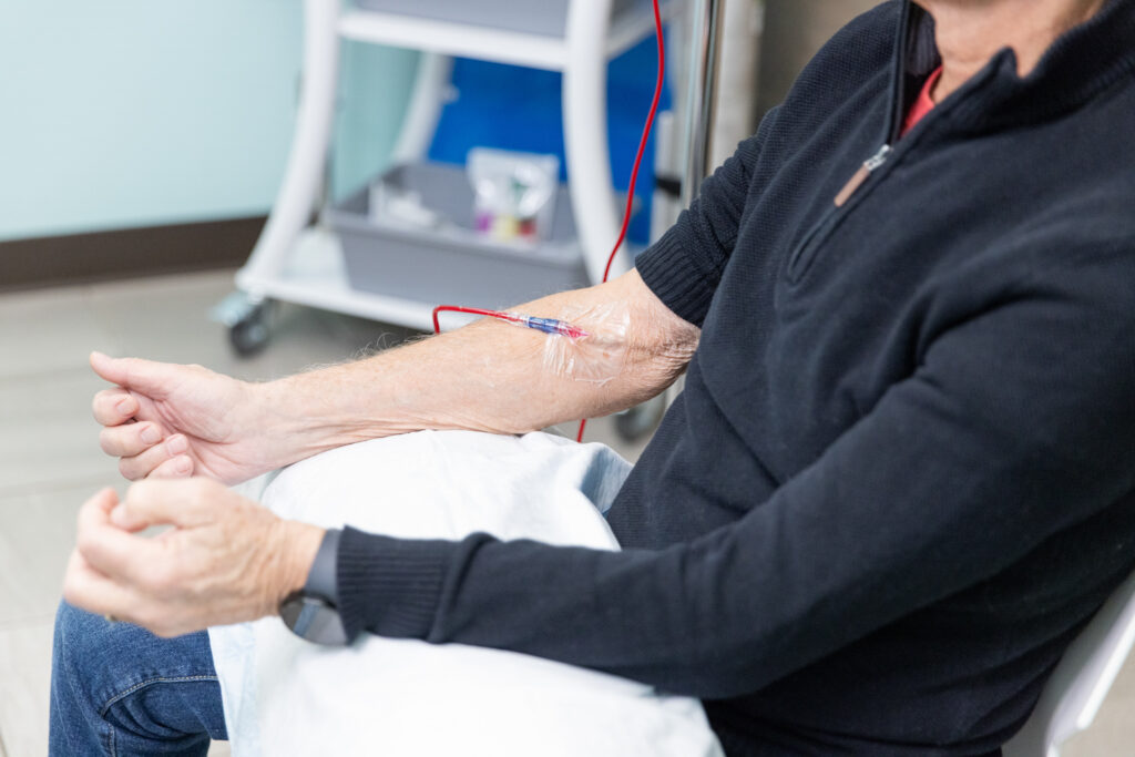 Patient sitting in wellness center with needle in arm for Ozone IV, a peripheral neuropathy treatment near Iowa City