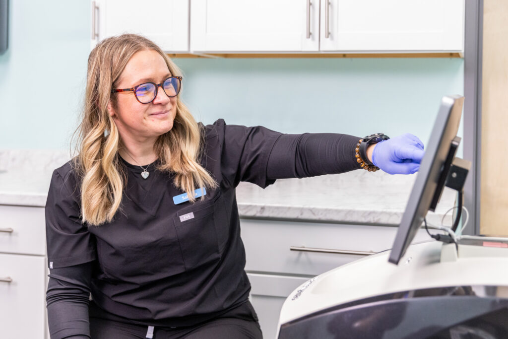 Medical provider smiles and points at computer screen at the weight loss clinic near Iowa City where she works