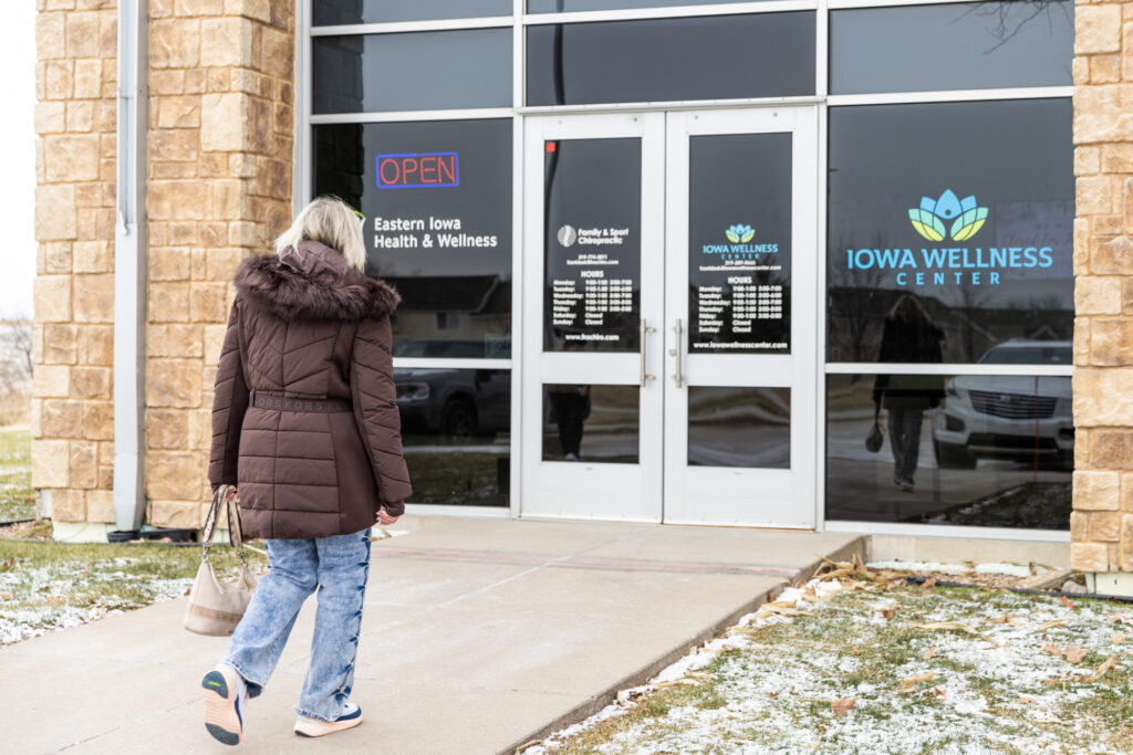 Woman wearing a big coat walks towards the entrance of Iowa Wellness Center. She is beginning a round of sessions for pelvic floor therapy near Iowa City.