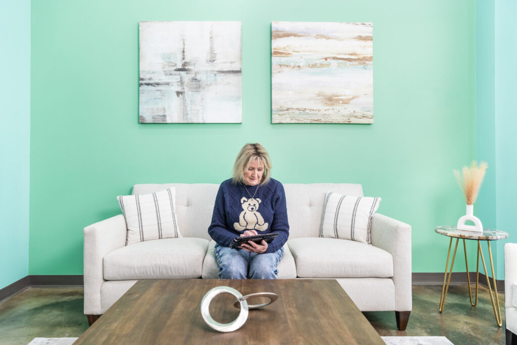 Woman sits on couch in the lobby of a wellness center and answers questions on a tablet regarding why she's interested in an IV infusion near Cedar Rapids.