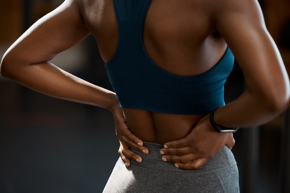 Person with hands on lower back to reduce pain with disc herniation treatment in North Liberty