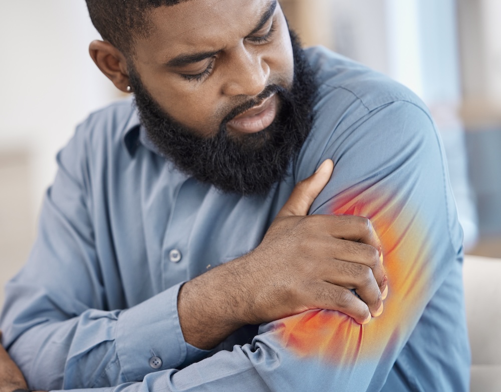 Man holds painful spot on arm to show the source of his discomfort and learn more about how to reduce inflammation in the body.
